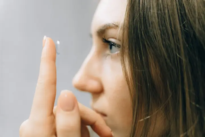 Woman placing a contact lens on her eye