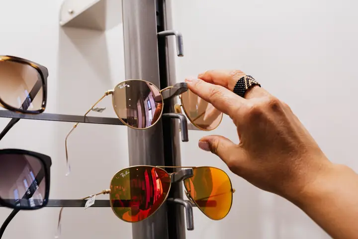 Hand picking a pair of sunglasses from a display rack